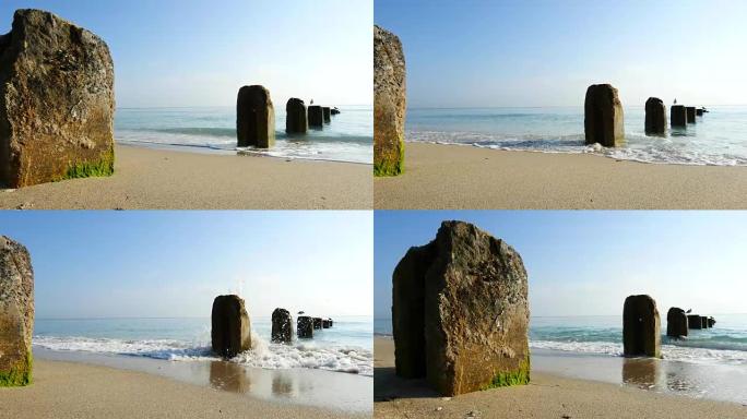 多莉拍摄了平静的海浪和平场景，用混凝土桩搭接在美丽的沙滩上