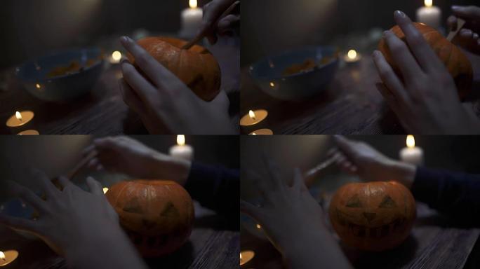 男性的手在晚上用蜡烛在木桌上sc出南瓜的种子和内容物。万圣节主题，杰克灯