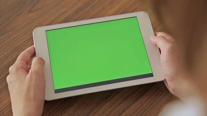 手握绿屏显示的漂亮女人平板电脑