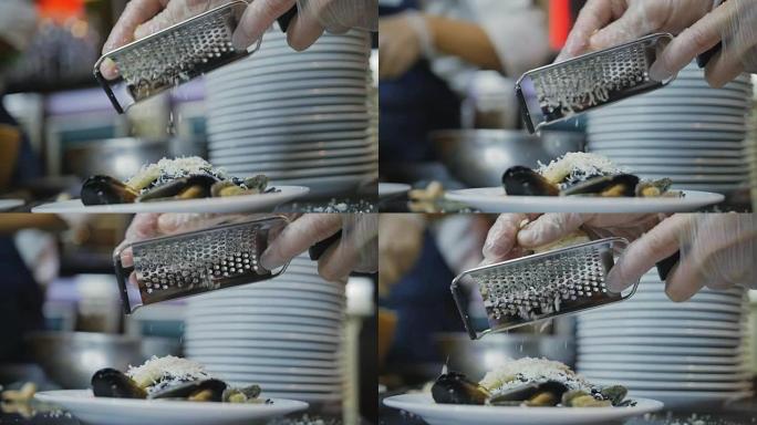 厨师用钢刨丝器将帕马森奶酪与意大利面放在盘子上的慢动作