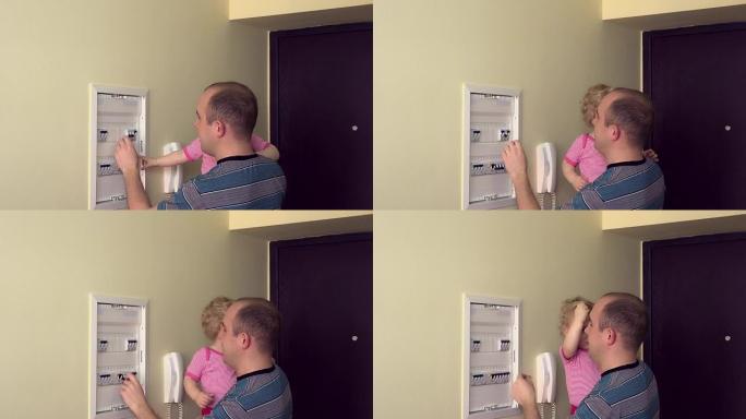 带女婴的男人在房间里检查断路器。全高清
