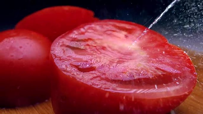 在切好的红番茄上洒水。冷色。超级慢动作镜头