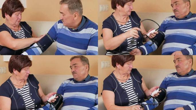 老年妇女在沙发上测量家里的血压。穷人的幸福。照顾妻子的丈夫