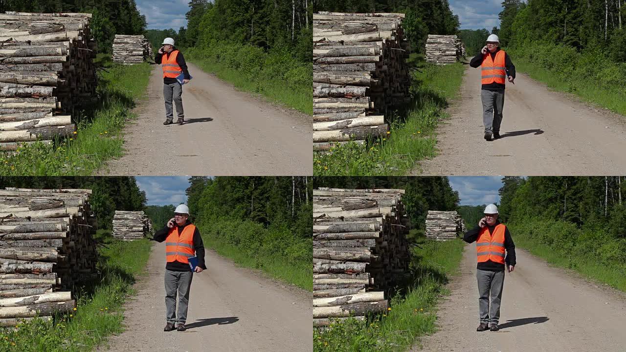 伐木工人在智能手机上聊天，在堆积物附近行走