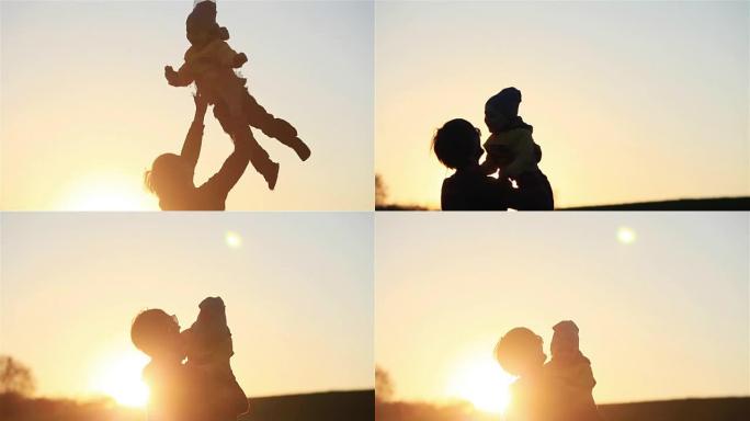 快乐的年轻父亲剪影将小儿子高高抛向空中日落时的草地自然乡村公园背光慢动作-家庭团聚快乐的童年年轻父亲