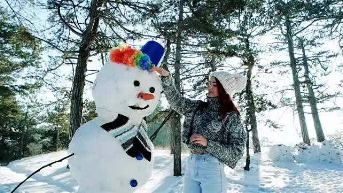 冬天森林里美丽的女孩在很多雪的背景下雕刻雪人，美丽的冬天，阳光明媚的日子