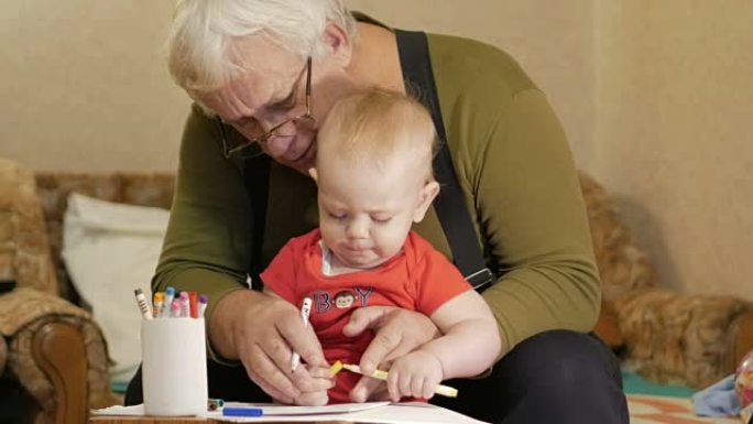 有吸引力的婴儿画与他的祖父在纸上的标记。孩子过敏，眼睛发红。孩子1年