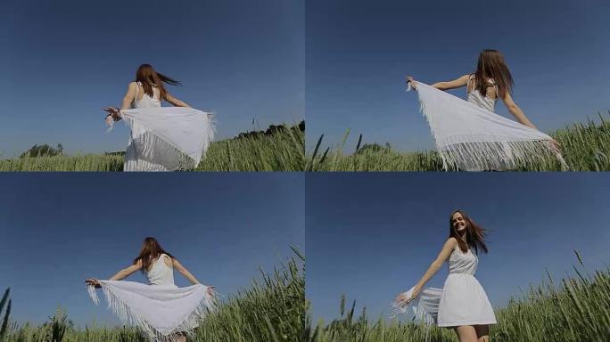 穿着白色连衣裙的漂亮女孩在户外野外玩得开心。慢动作。快乐微笑的年轻女子享受大自然。自由概念。年轻漂亮