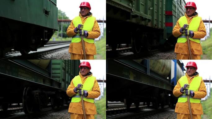 戴着红色安全帽的铁路工人站在铁轨旁看着货车