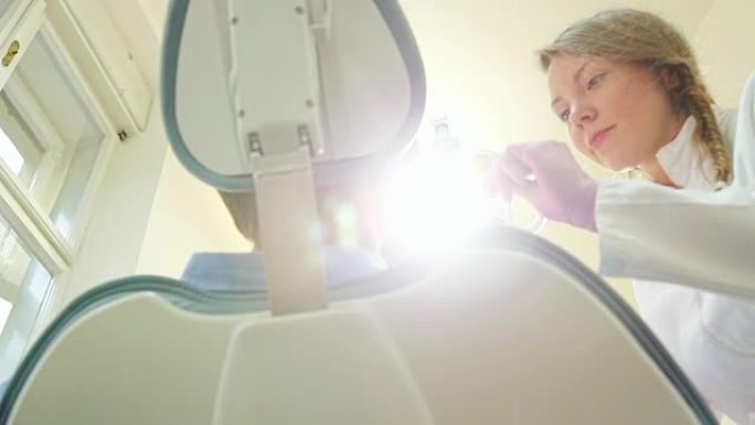 友好的女牙医打开灯并检查患者的牙齿