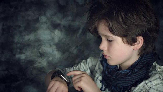 4k高科技拍摄的孩子看着他的智能手表，然后对着相机