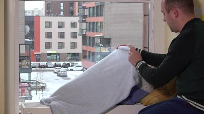 细心的父亲爱抚着他的孩子躺在窗户附近的散热器上。降雪