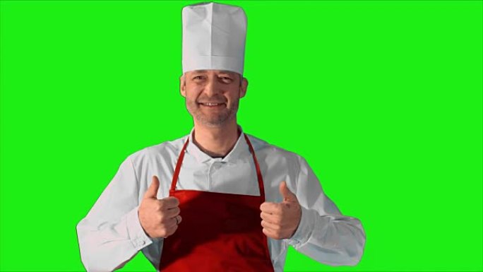 英俊的成年厨师竖起大拇指对着镜头，在绿色背景上微笑