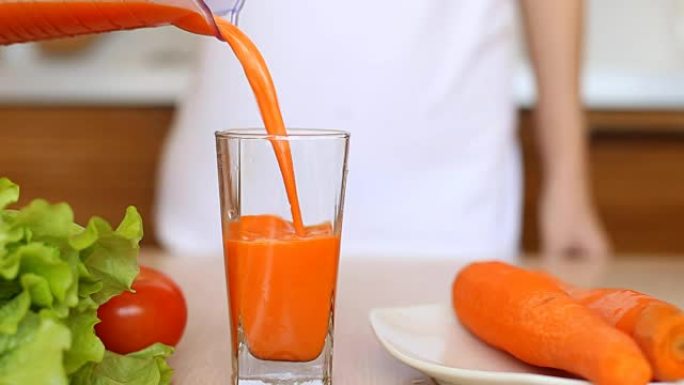 玻璃杯的特写镜头，倒入胡萝卜汁。