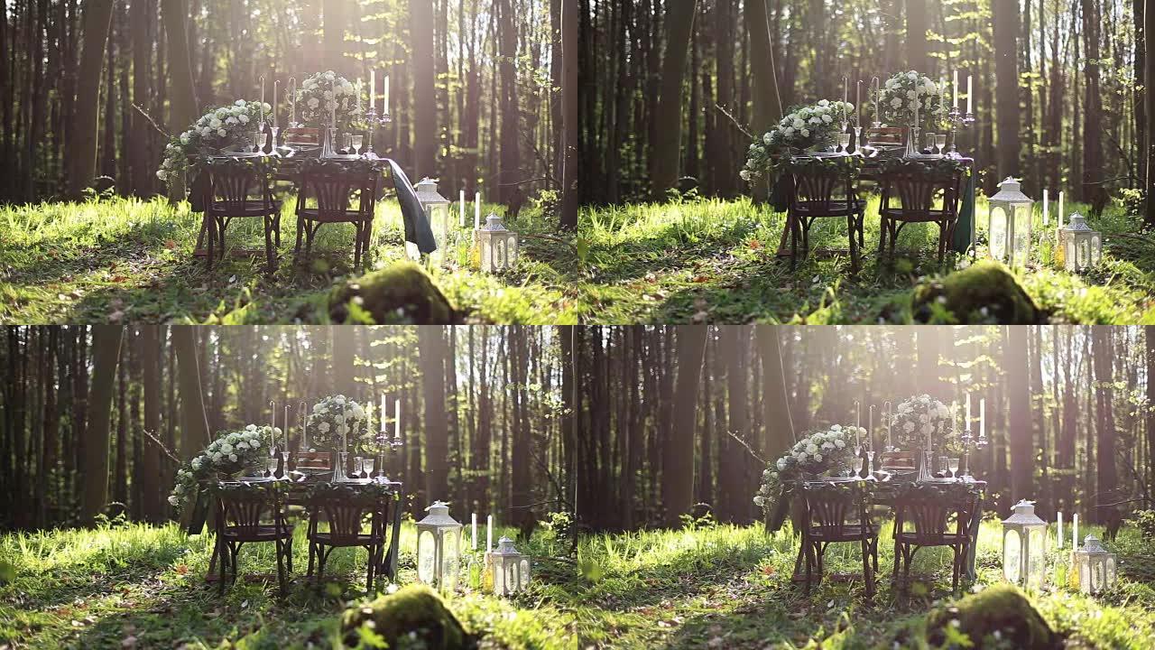婚礼装饰的桌子在森林里为两个人设置。白玫瑰花束和带灯笼的老式蜡烛的婚礼装饰。