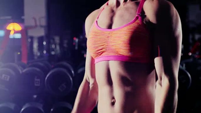 女运动员在健身房用哑铃做运动。在聚光灯下