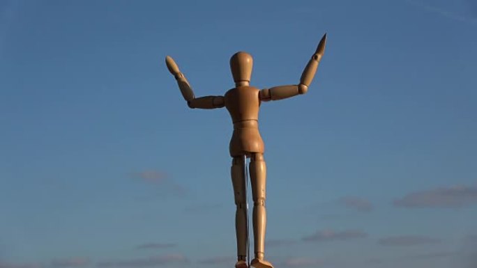 木制艺术家人体模型在蓝天背景上旋转