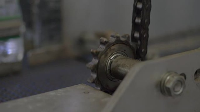 矿泉水和瓶子厂机器中的旋转齿轮。使用中的专业工业输送机的特写镜头。详细介绍了工作输送机齿轮。工业设备