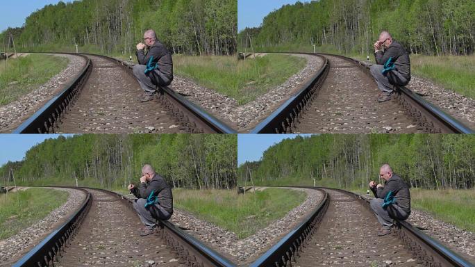 沮丧的残疾男子拐杖坐在铁路上哭泣