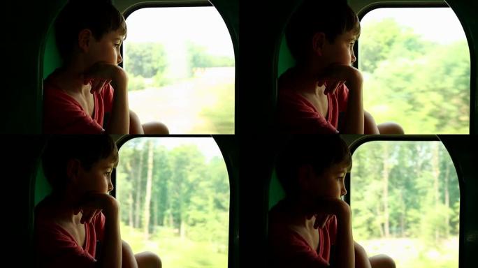 沉思的孩子在看着火车窗外时做白日梦。孩子看着火车窗外，脸上带着体贴的表情思考。坐火车旅行的小男孩