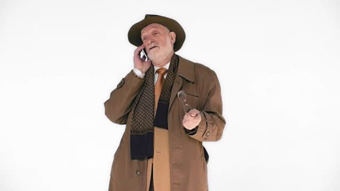 一位戴着帽子的老人在白色背景上打电话。他笑得很轻松