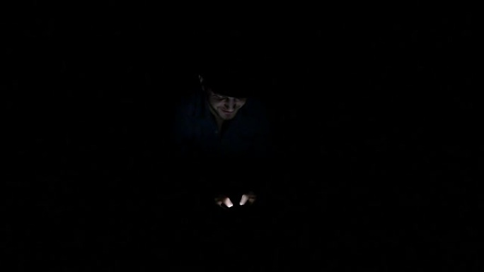 一个人在黑暗中独自在智能手机上发短信，说明技术奴隶的概念