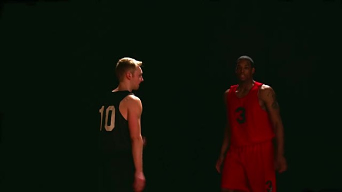 篮球运动员在黑色背景下捍卫对手