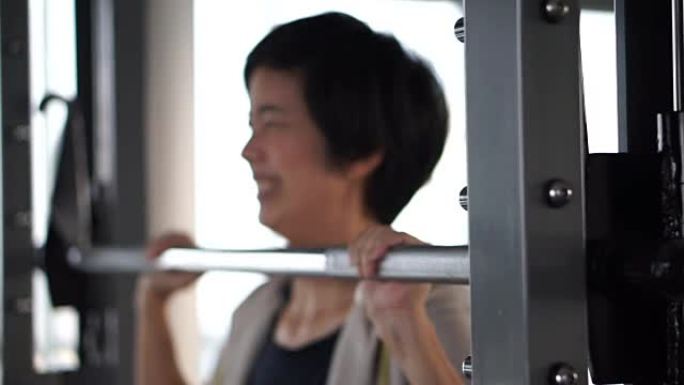亚洲成年女运动员在健身馆锻炼做机器举重