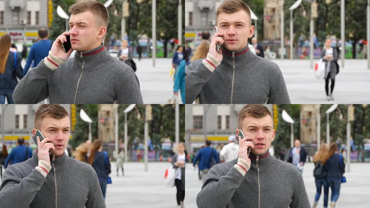 城市广场上一个年轻英俊男子用手机说话的肖像。特写
