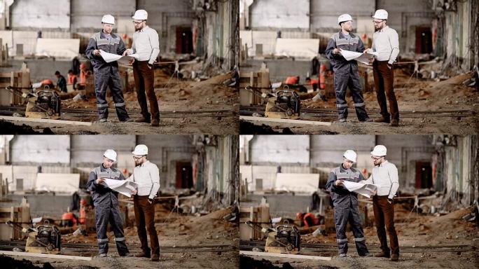 两名戴着安全帽的男子站在建筑区域，看着未来的建筑方案。工头指向图纸并向工人解释当前组装的亮点