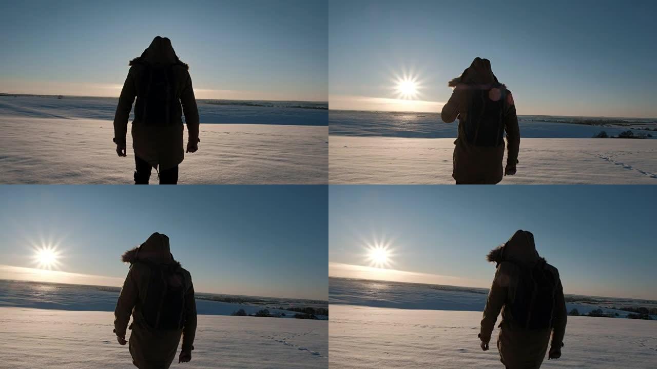 一个穿着背包的夹克的男人在冬天的日落中上场