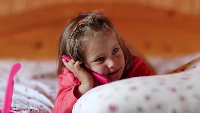 带智能手机的小女孩躺在床上