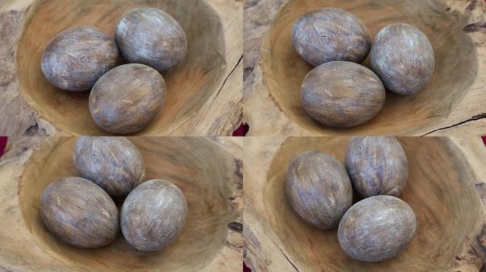 旋转桌上一个木碗中的三个棕色木蛋