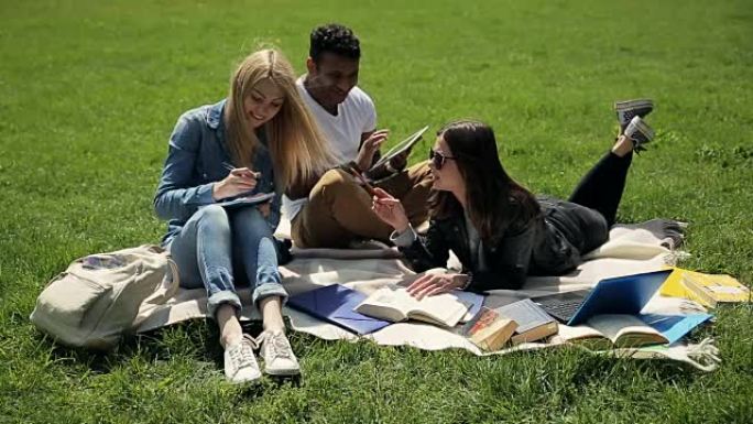 三人学生在校园草坪上学习。