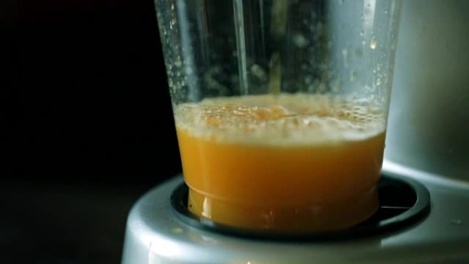 榨汁机的汁液倒入杯子中。特写