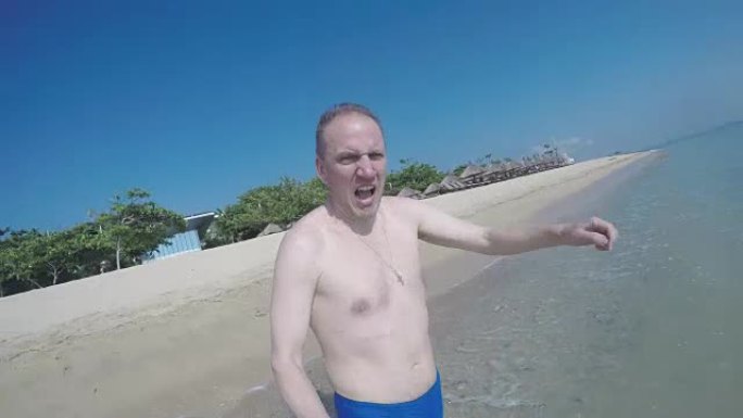 那个在海滩上表情非常严肃的男人在海里奔跑，掉进水里游泳