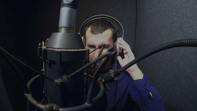 戴着耳机的男人歌手在录音室唱歌