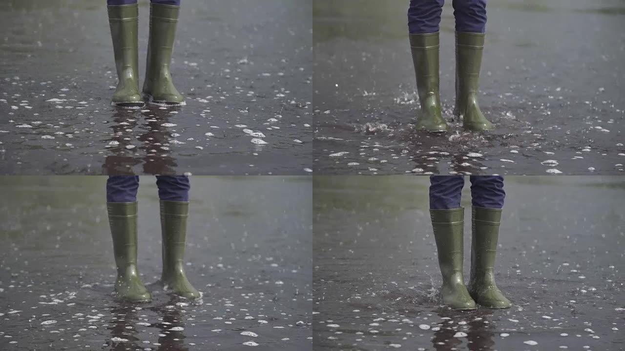 一个穿橡胶靴的女人跳过水坑。慢动作