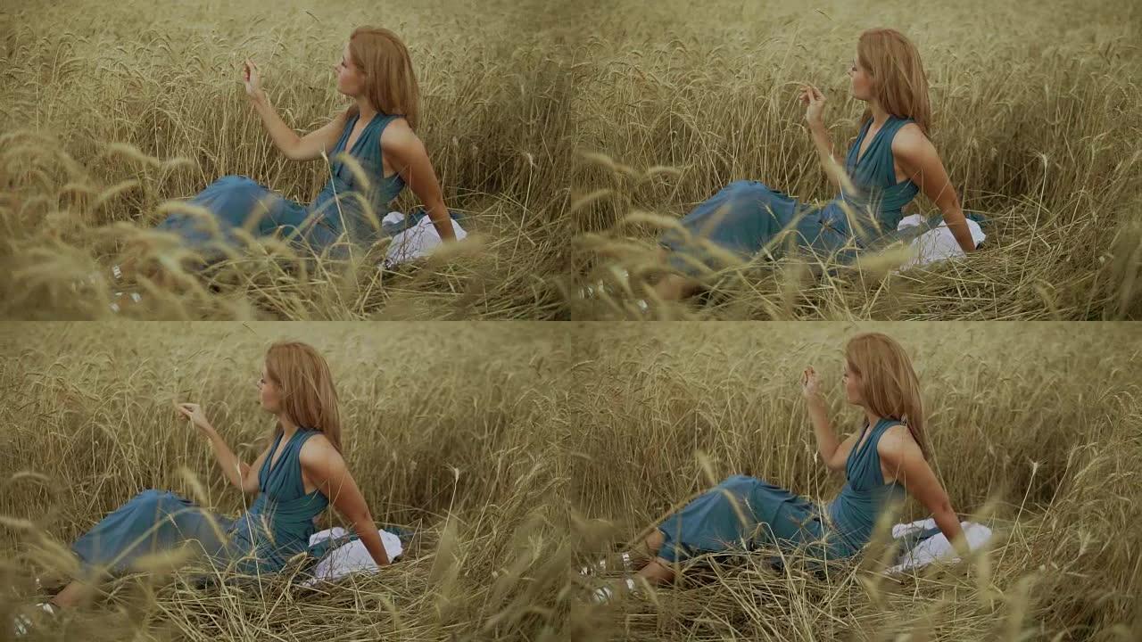 迷人的年轻女子坐在金色的麦田里。她的手在摸麦穗。收获概念。收获。慢动作镜头