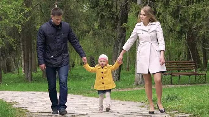 带着女婴在公园散步的家庭。慢慢地