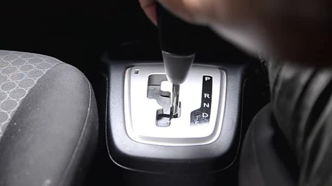 在汽车上使用自动变速器的人的手