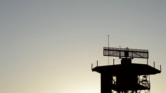 飞机在机场日落时从雷达电信塔上起飞