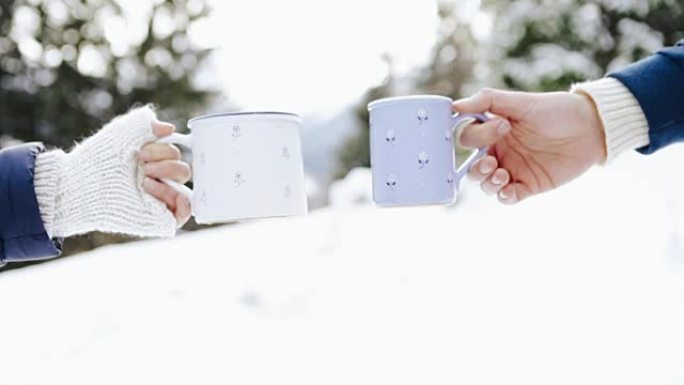 男人和女人在冬季森林林间空地上用一杯热茶编织手套