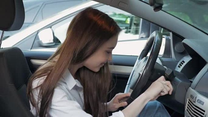 年轻可爱的幸福女人在拿到驾照后展示车钥匙。美丽的年轻驾驶学生在第一时间启动汽车