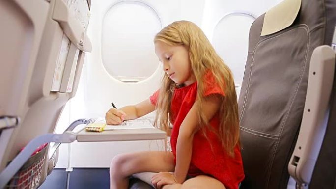坐在飞机窗边的可爱的小女孩坐飞机旅行。儿童用彩色铅笔画画