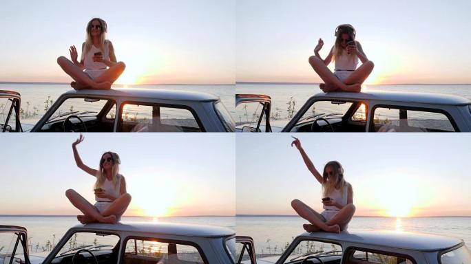 夏天的汽车旅行，女孩在车顶的汽车上听耳机听音乐，女性在汽车上享受日落时的好音乐，快乐的旅程