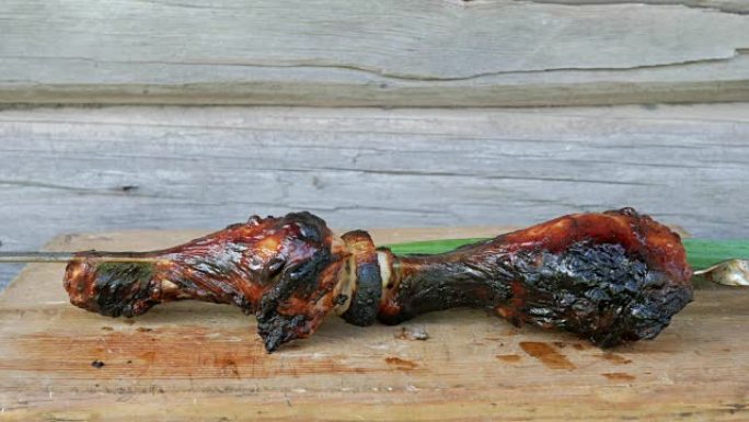 在带有大葱的木板上的烧烤中煮熟的肉。红润，轻微烧焦的碎片。背景上的木墙