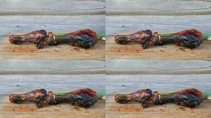 在带有大葱的木板上的烧烤中煮熟的肉。红润，轻微烧焦的碎片。背景上的木墙