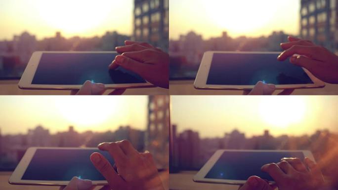 女人的手在城市模糊的日落剪影处使用平板电脑