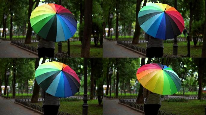 在城市公园的雨天，一个面目全非的女人带着五颜六色的雨伞行走